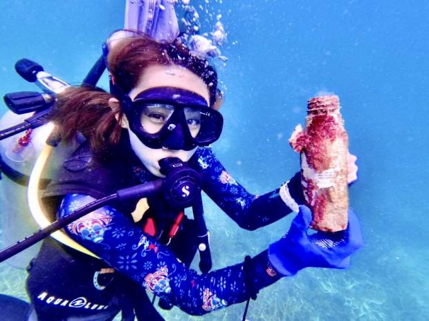 female diver picking trash up from undewater