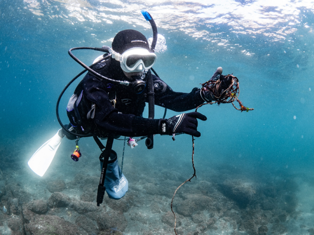 female diver picking trash up from undewater in Izu